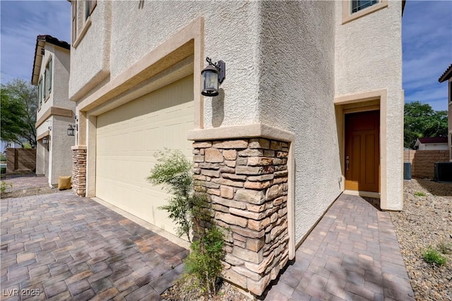 view of side of home featuring stucco siding, stone siding, and a garage