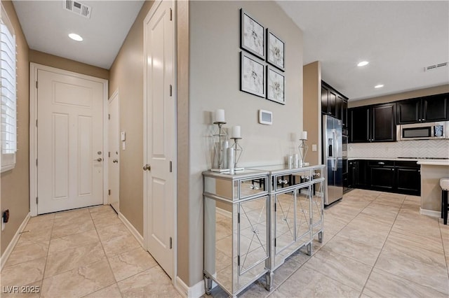 kitchen with appliances with stainless steel finishes, backsplash, dark cabinets, baseboards, and recessed lighting