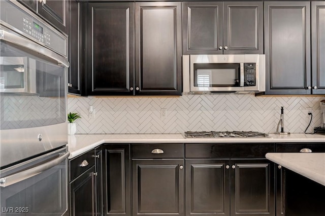 kitchen featuring stainless steel appliances, light countertops, and backsplash
