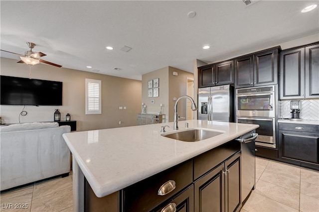 kitchen with a sink, appliances with stainless steel finishes, light tile patterned flooring, a kitchen island with sink, and recessed lighting