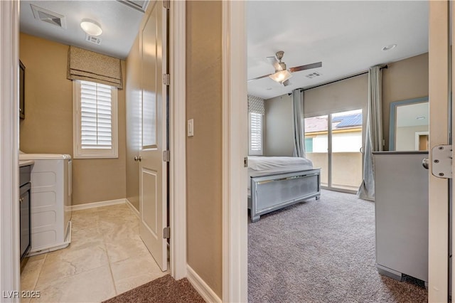 hallway with washer / clothes dryer, light colored carpet, and baseboards