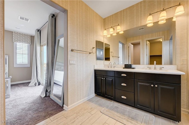 full bathroom featuring baseboards, double vanity, wallpapered walls, and wood finished floors