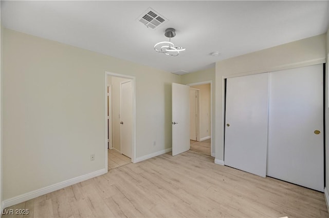 unfurnished bedroom featuring light wood-type flooring, baseboards, and a closet