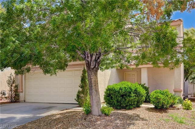 obstructed view of property with concrete driveway, stucco siding, and a garage