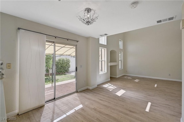 empty room with a chandelier, a smoke detector, baseboards, and light wood-style floors