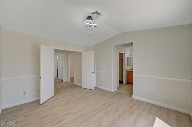 unfurnished bedroom with light wood-type flooring, vaulted ceiling, and baseboards