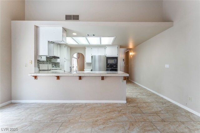 4378 Cherrystone Ct, Las Vegas, NV 89121 - kitchen with black appliances, tile countertops, a peninsula, and a kitchen breakfast bar