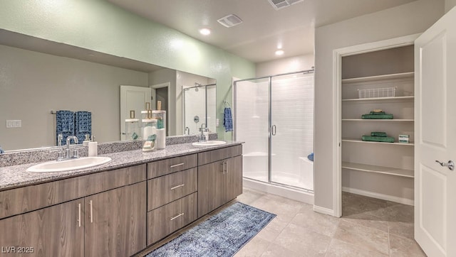 bathroom featuring a shower stall, double vanity, tile patterned floors, and recessed lighting