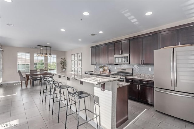 3165 Via Como Dr, Henderson, NV 89044 - kitchen featuring stainless steel appliances, decorative backsplash, a breakfast bar area, light stone countertops, and recessed lighting