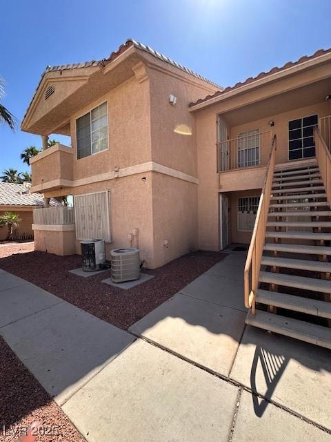1830 N Pecos Rd Unit 155, Las Vegas, NV 89115 - view of side of property featuring stairs, stucco siding, a tile roof, and central AC unit