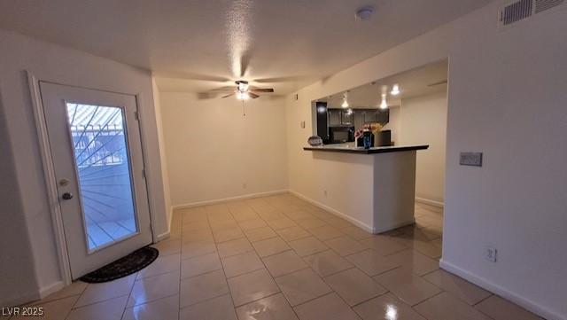 1830 N Pecos Rd Unit 155, Las Vegas, NV 89115 - kitchen featuring a ceiling fan, a peninsula, baseboards, light tile patterned flooring, and black microwave