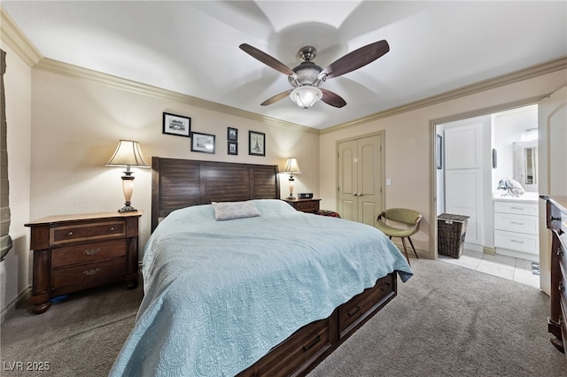 carpeted bedroom featuring ornamental molding, baseboards, a closet, ceiling fan, and ensuite bathroom