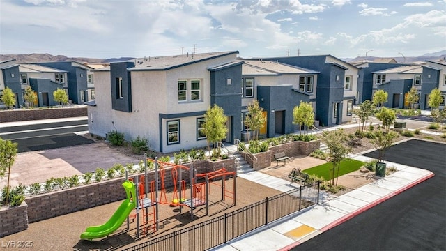 rear view of property featuring a residential view, stucco siding, fence, and a playground