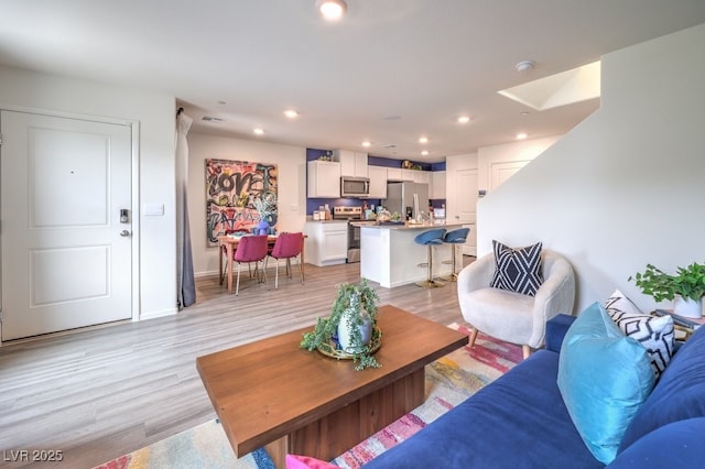 living area featuring light wood finished floors, recessed lighting, and baseboards