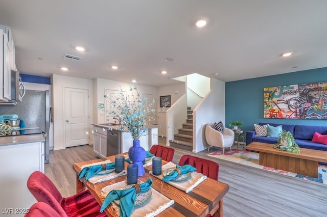 dining space featuring light wood-type flooring, stairs, and recessed lighting