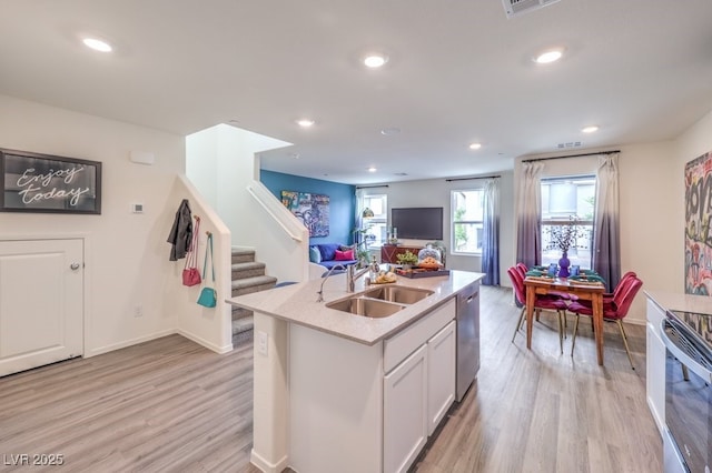 kitchen featuring a sink, open floor plan, light wood finished floors, appliances with stainless steel finishes, and recessed lighting