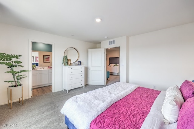 bedroom with light carpet, ensuite bathroom, and baseboards