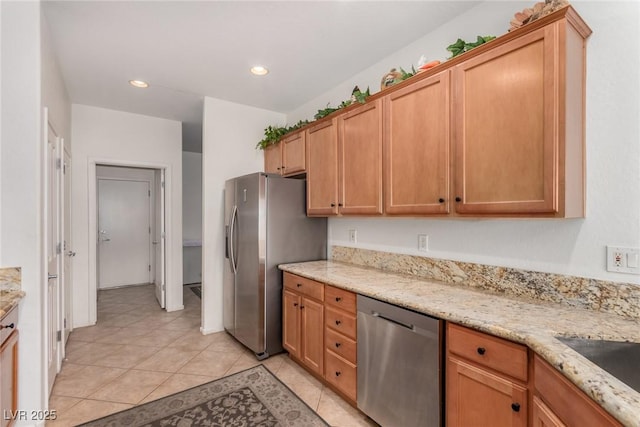 kitchen featuring appliances with stainless steel finishes, light tile patterned floors, light stone countertops, recessed lighting, and a sink