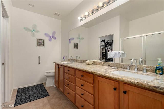 full bath featuring a stall shower, tile patterned floors, double vanity, toilet, and a spacious closet