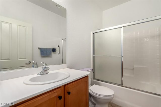 full bath with toilet, vanity, and shower / bath combination with glass door