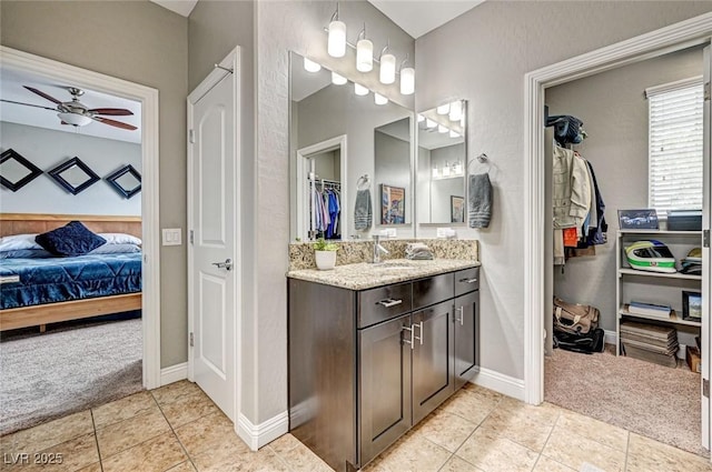 2159 Morro Vista Dr, Las Vegas, NV 89135 - ensuite bathroom featuring tile patterned flooring, baseboards, vanity, ceiling fan, and a spacious closet