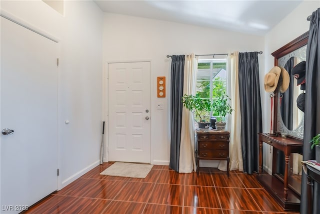 foyer entrance with vaulted ceiling and baseboards
