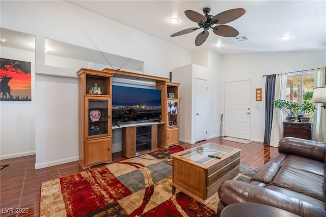 living room with ceiling fan, wood finished floors, baseboards, a dry bar, and vaulted ceiling