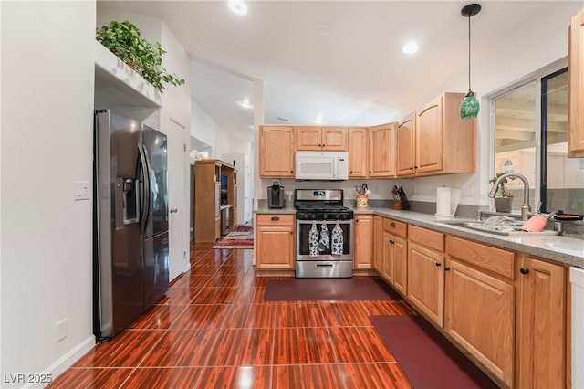 kitchen with appliances with stainless steel finishes, light brown cabinets, a sink, hanging light fixtures, and light countertops