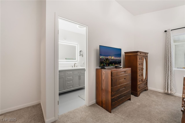 bedroom with light carpet, a sink, connected bathroom, and baseboards