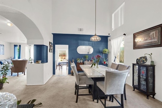 3389 Commendation Dr, Las Vegas, NV 89117 - dining room featuring a towering ceiling, carpet floors, arched walkways, a chandelier, and baseboards