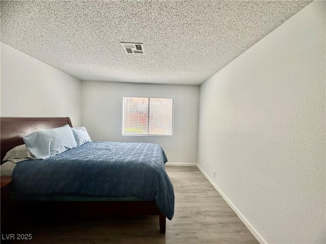 3151 Soaring Gulls Dr Unit 1023, Las Vegas, NV 89128 - bedroom featuring light wood-type flooring, a textured ceiling, and baseboards