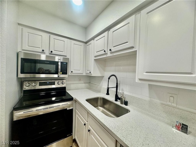 3151 Soaring Gulls Dr Unit 1023, Las Vegas, NV 89128 - kitchen with appliances with stainless steel finishes, a sink, white cabinets, and decorative backsplash