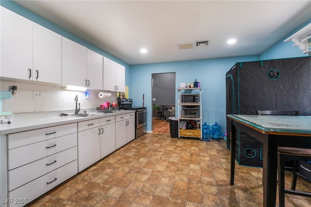 120 N Phyllis St, Las Vegas, NV 89110 - kitchen featuring appliances with stainless steel finishes, a sink, light countertops, decorative backsplash, and white cabinetry