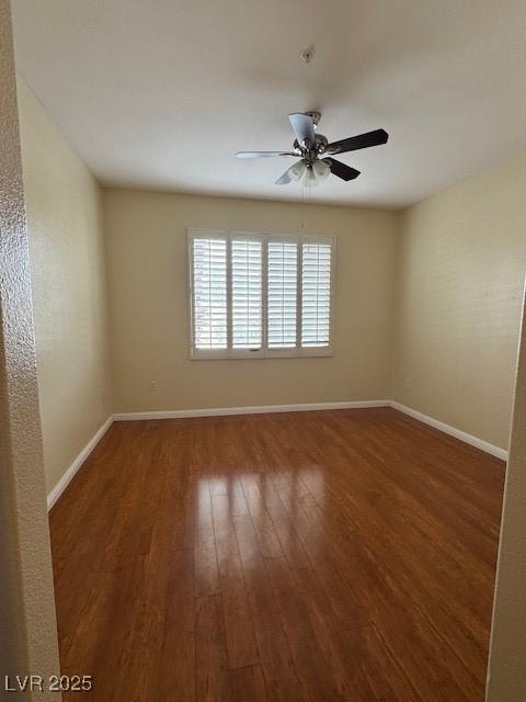 empty room with wood finished floors, a ceiling fan, and baseboards