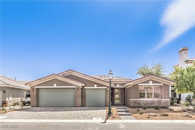 ranch-style house featuring an attached garage, stucco siding, decorative driveway, and a tile roof