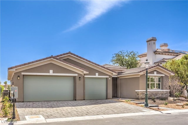 ranch-style house featuring stucco siding, decorative driveway, an attached garage, a tiled roof, and central AC unit