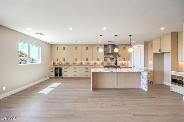 kitchen featuring wall chimney range hood, beverage cooler, tasteful backsplash, a sink, and recessed lighting