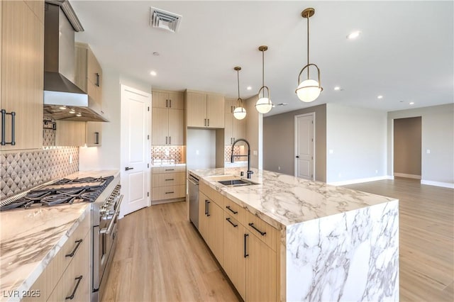 kitchen featuring stainless steel appliances, a sink, light brown cabinetry, light wood-style flooring, and recessed lighting