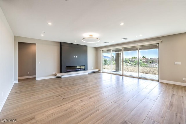 unfurnished living room featuring baseboards, light wood finished floors, a fireplace, and recessed lighting