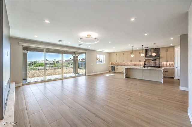 unfurnished living room with baseboards, recessed lighting, light wood-type flooring, and a sink