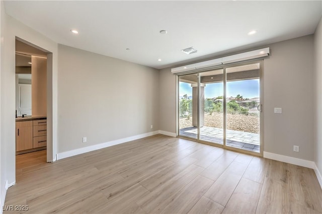 spare room featuring light wood finished floors, baseboards, and recessed lighting