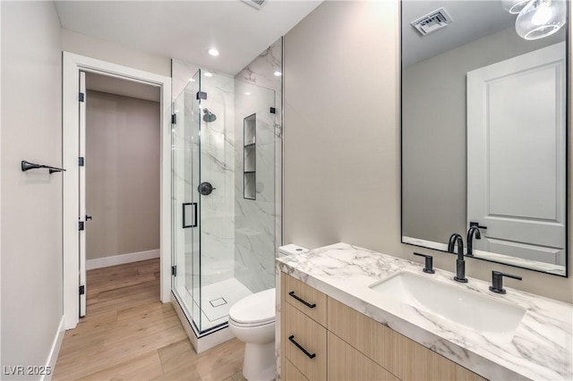 full bathroom featuring a marble finish shower, toilet, wood finished floors, vanity, and recessed lighting