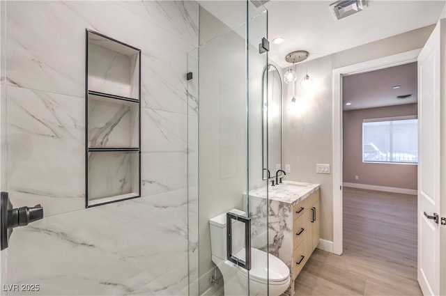 bathroom featuring vanity, a marble finish shower, wood finished floors, toilet, and baseboards