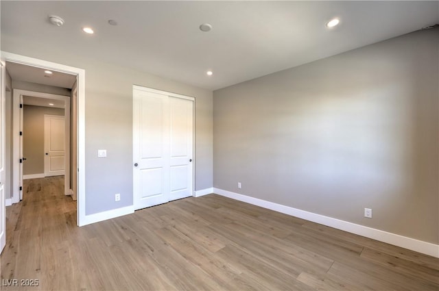 unfurnished bedroom with baseboards, light wood-style floors, recessed lighting, and a closet