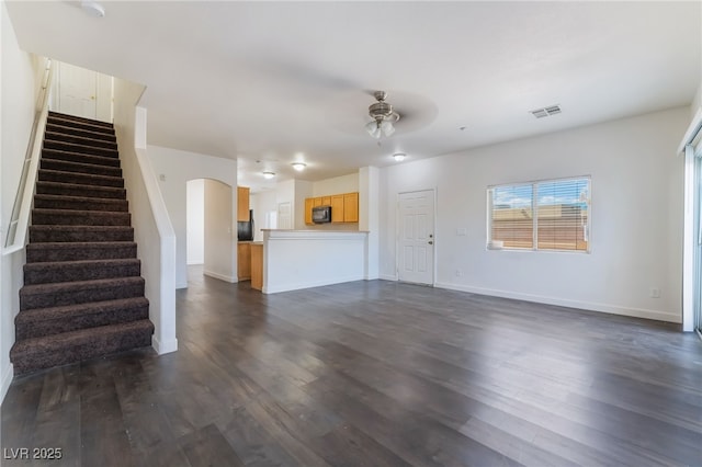 unfurnished living room with a ceiling fan, dark wood-type flooring, stairway, and baseboards
