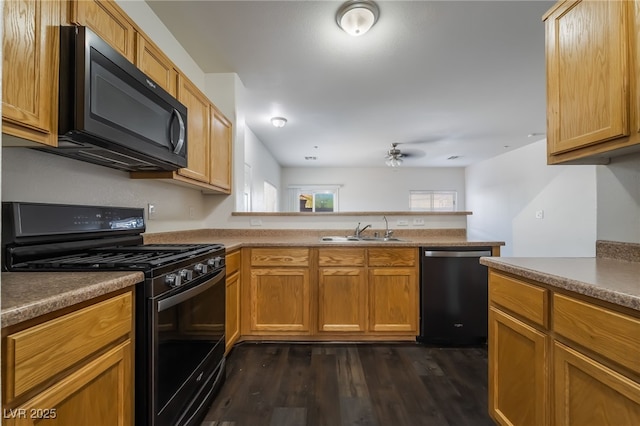 kitchen with black appliances, a sink, a peninsula, dark wood-type flooring, and a ceiling fan