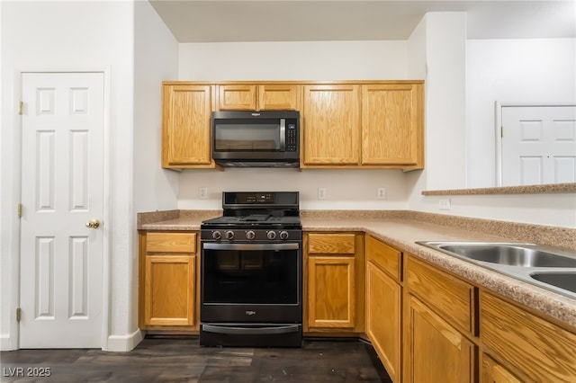 kitchen featuring black appliances, dark wood finished floors, light countertops, and a sink