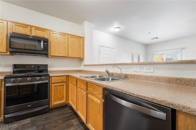 kitchen featuring black appliances, a sink, dark wood-style floors, and light countertops