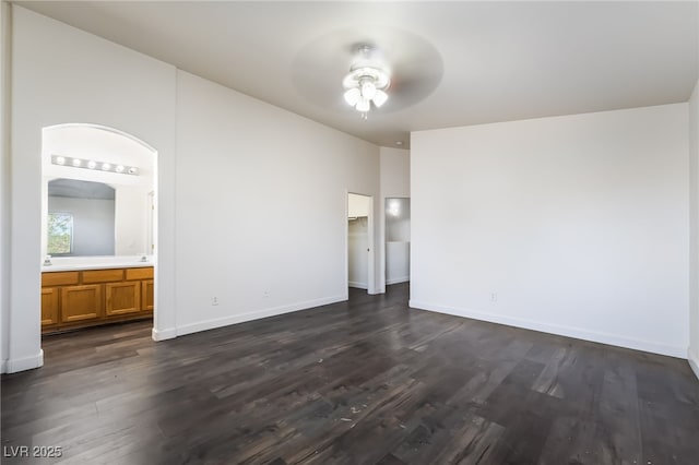 unfurnished bedroom with dark wood finished floors, baseboards, and connected bathroom