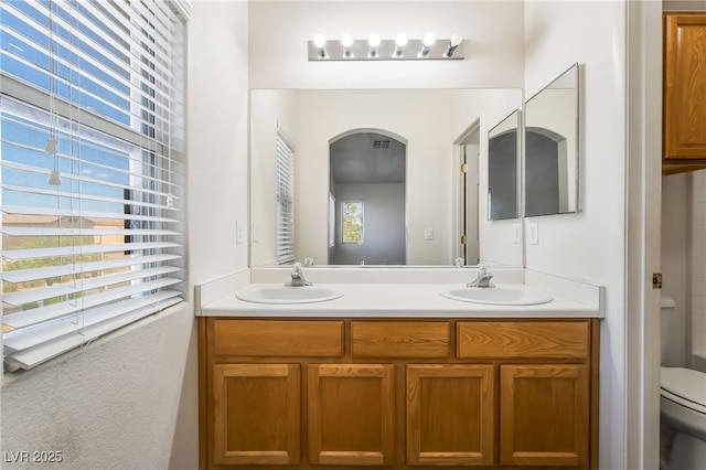 bathroom with toilet and double vanity